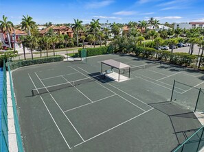 A tennis court with a covered seating area, surrounded by palm trees and residential buildings. - Welcome to F203, 2br/2bath, Sundial of Sanibel, a relaxing beach condo, resort-style amenities, and easy access to sand, shells, dining, and island fun. Perfect for a Sanibel getaway with comfort, convenience, and coastal charm. 3-7night minimum (Sanibel Island)