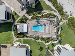 An aerial view of a resort with a swimming pool, sun loungers, and palm trees. - Welcome to F203, 2br/2bath, Sundial of Sanibel, a relaxing beach condo, resort-style amenities, and easy access to sand, shells, dining, and island fun. Perfect for a Sanibel getaway with comfort, convenience, and coastal charm. 3-7night minimum (Sanibel Island)