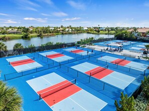 A tennis court complex with multiple courts, a viewing area, and a body of water in the background. - Welcome to F203, 2br/2bath, Sundial of Sanibel, a relaxing beach condo, resort-style amenities, and easy access to sand, shells, dining, and island fun. Perfect for a Sanibel getaway with comfort, convenience, and coastal charm. 3-7night minimum (Sanibel Island)