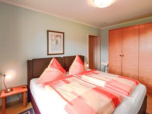 Ein Hotelzimmer mit Bett, Nachttisch, gerahmtem Bild an der Wand und Kleiderschrank.