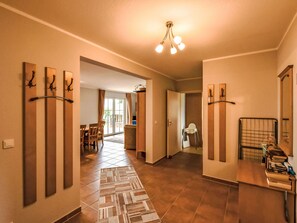 A hotel hallway with a tiled floor, a dining area with a table and chairs, and a kitchen area with a counter and appliances. - Boddenblick - EG by Interhome (Gingst)