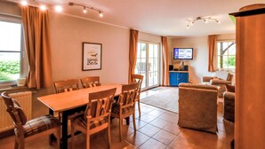 Amplia sala de estar con una mesa de comedor, sillas, un sofá y un televisor.