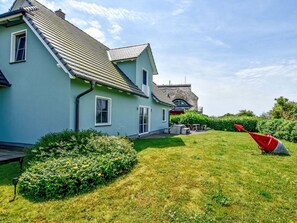 Ein Haus mit Satteldach, einer Veranda und einem gepflegten Rasen.