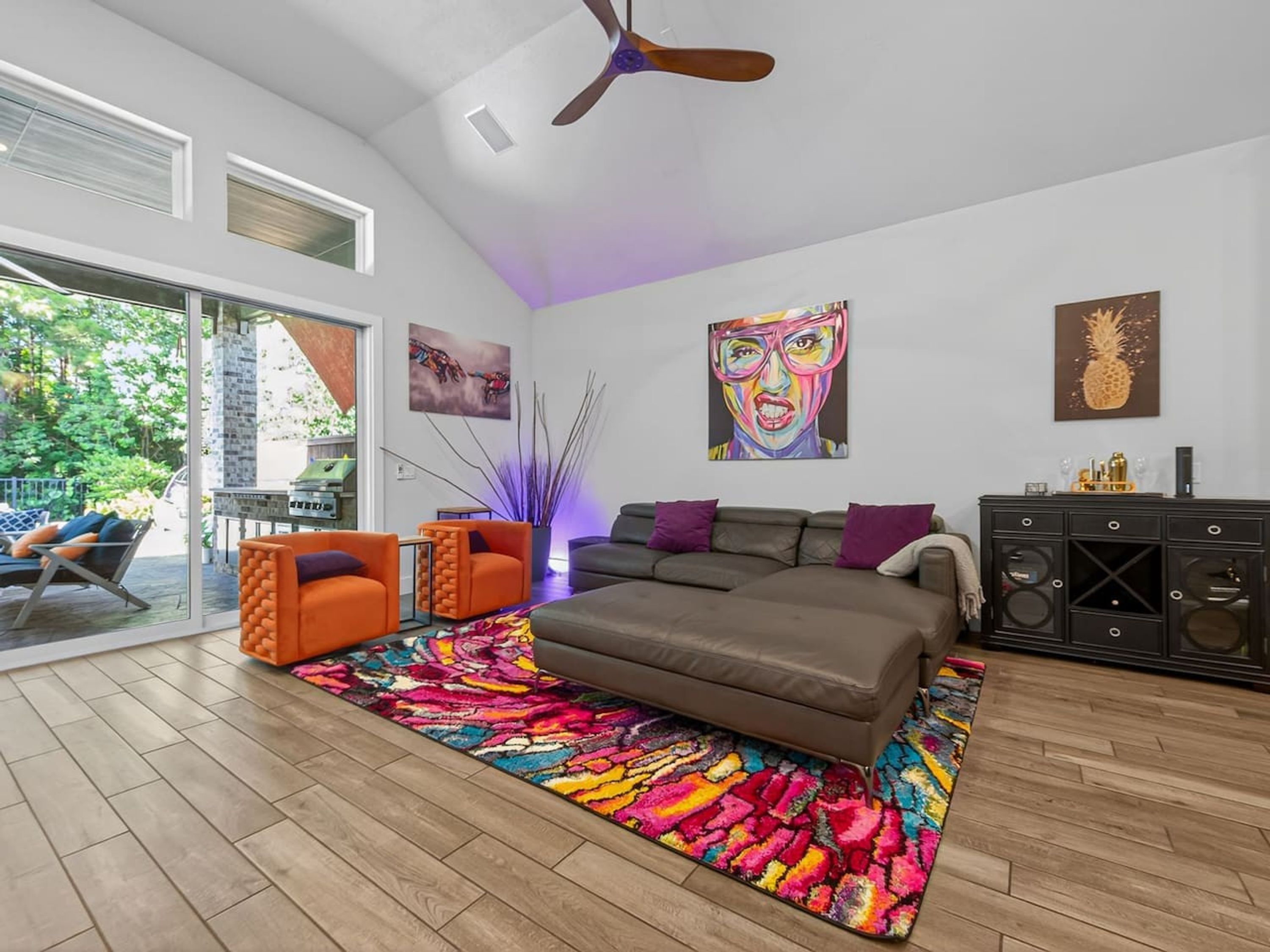 A modern living room with a sofa, chairs, a coffee table, a fireplace, and artwork on the walls.