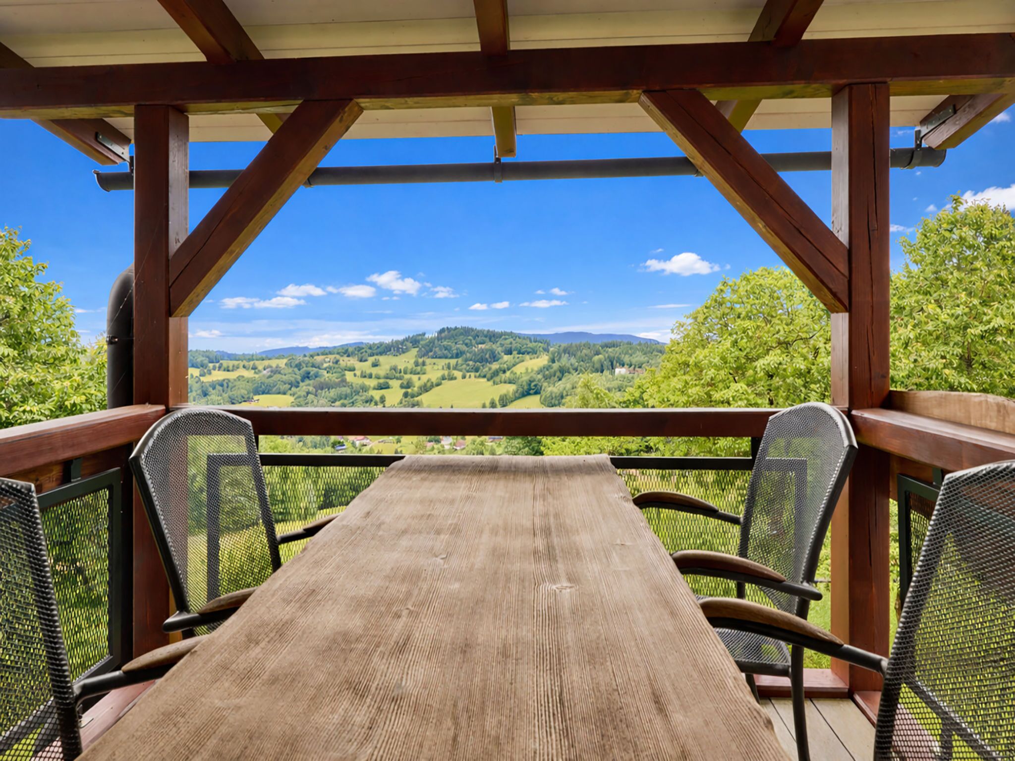 A wooden deck with a table and chairs, overlooking a scenic landscape.