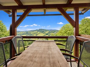 Eine Holzterrasse mit Tisch und Stühlen, mit Blick auf eine reizvolle Landschaft.