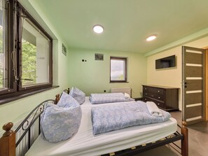 Ein Schlafzimmer mit Bett, Kommode, Fenster und Tür.