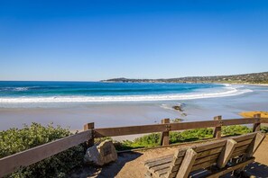 A wooden bench overlooking a beach with clear blue water and a distant shoreline. - 4083 Seabright - In the Cultural Center of Carmel (Carmel-by-the-Sea)