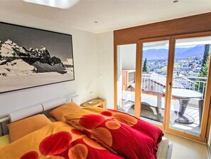 A bedroom with a bed, a painting, and a balcony with a view. - Casa Jörger by Interhome (Flims)