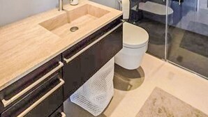 Uma casa de banho moderna com um espelho grande, lavatório, sanita e área de duche.