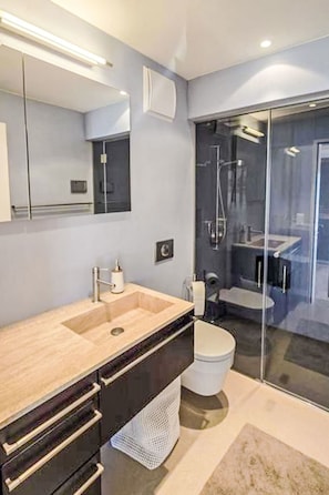 Ein modernes Badezimmer mit großem Spiegel, Waschbecken, Toilette und Duschbereich.