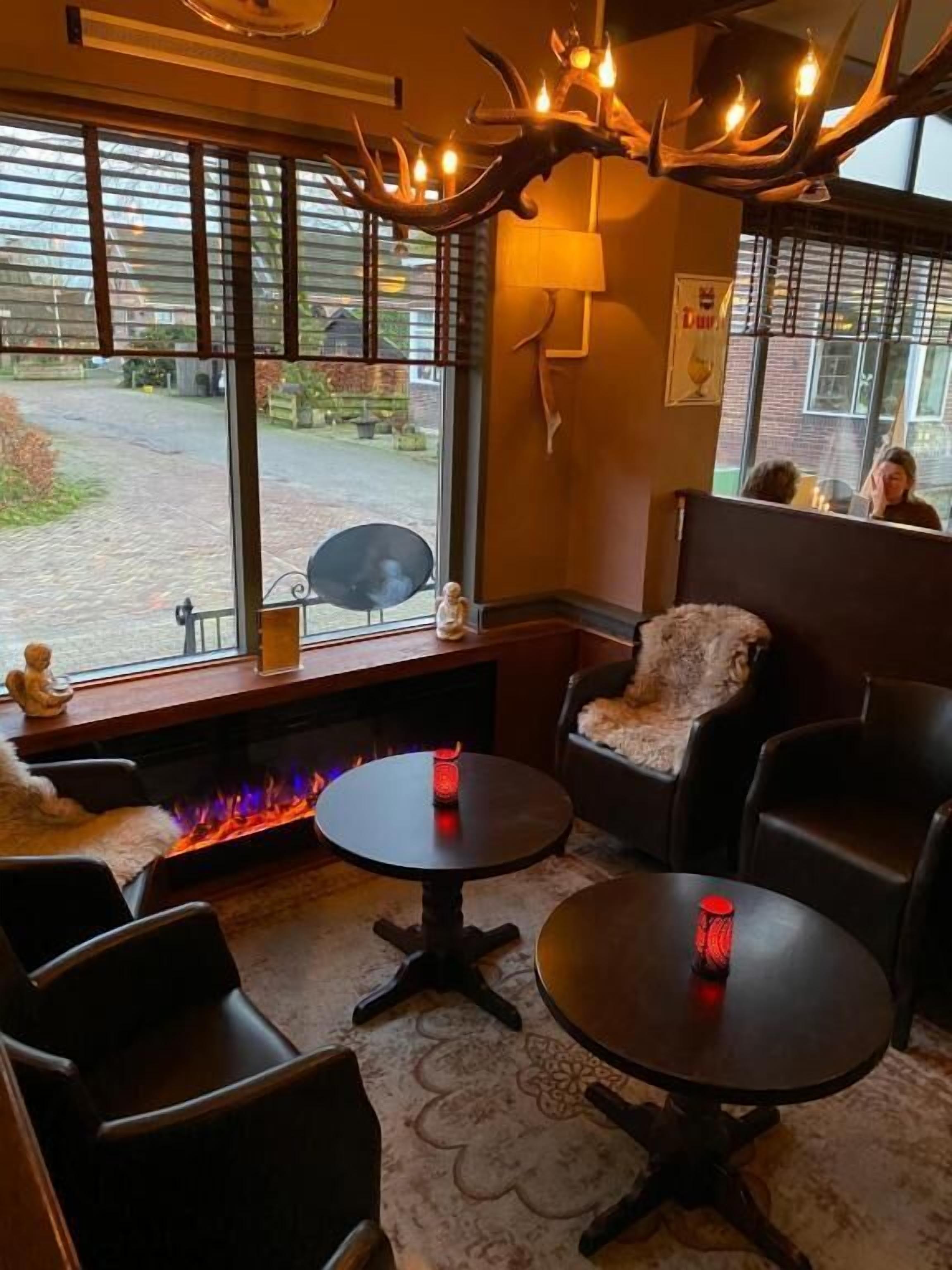 Una habitación acogedora con chimenea, mesas redondas y asientos cómodos.
