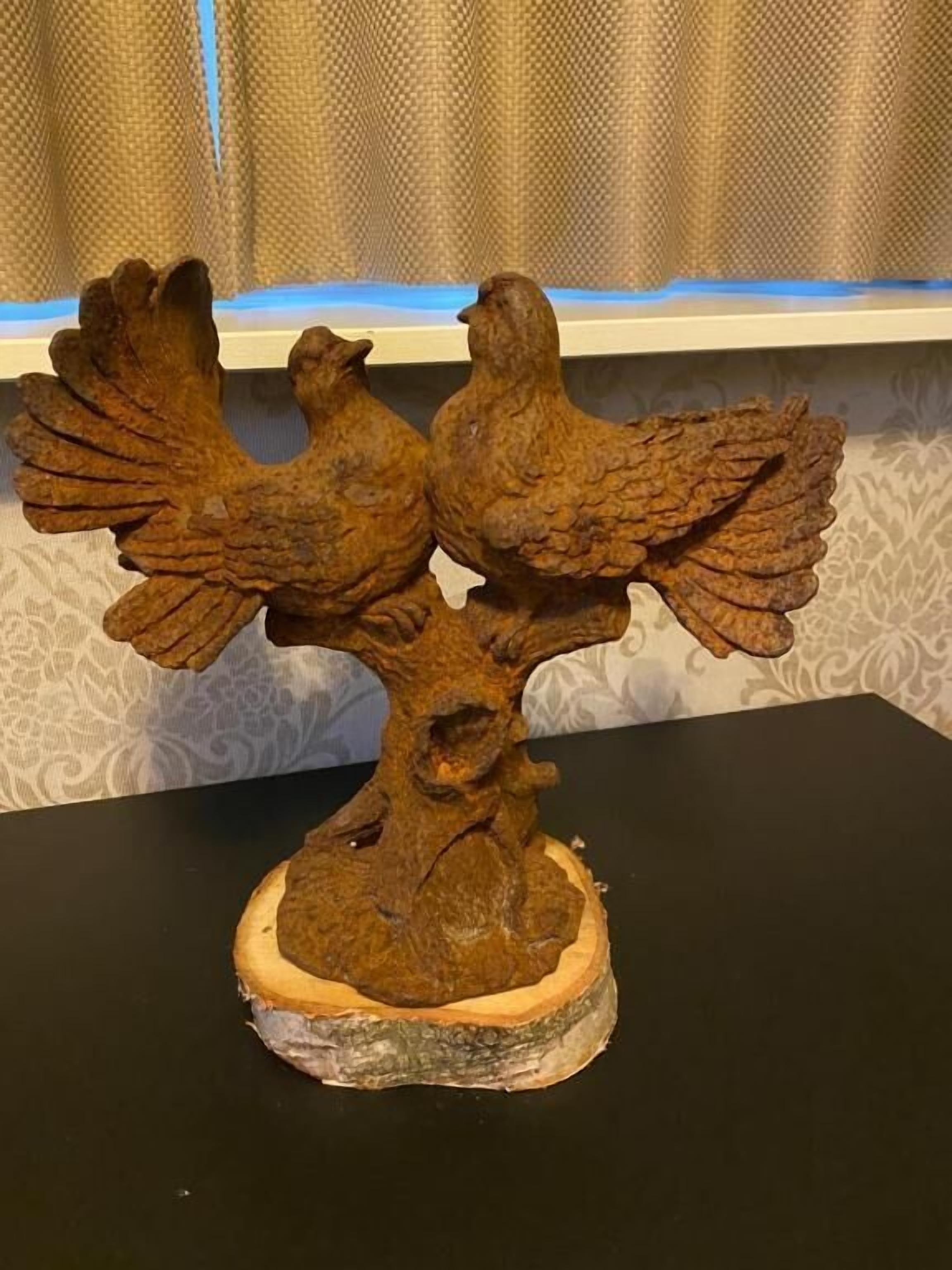 A wooden sculpture of two birds perched on a tree branch.