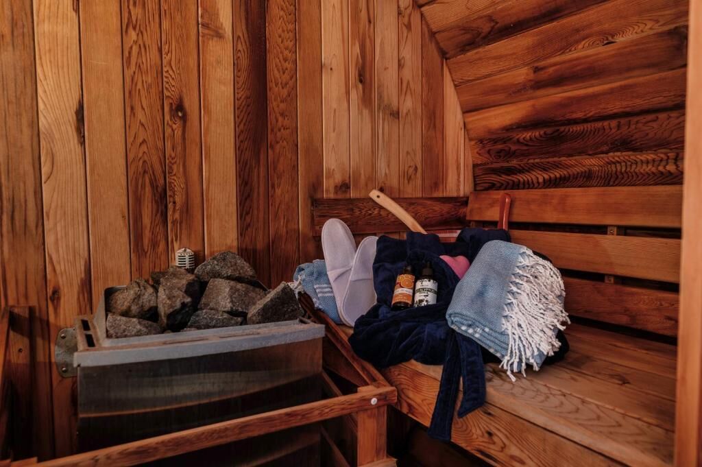 Ein Holzblockhaus-Innenraum mit einer Bank, einem Holzscheitkorb und einer Decke.
