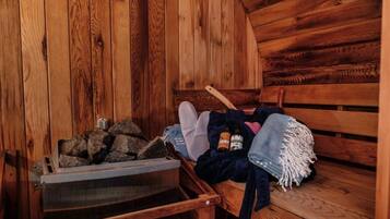 Ein Holzblockhaus-Innenraum mit einer Bank, einem Holzscheitkorb und einer Decke.