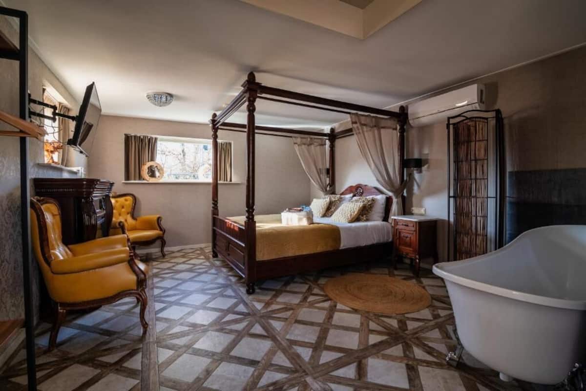 A bedroom with a four-poster bed, a clawfoot bathtub, and a patterned floor.