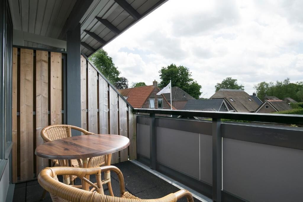 A balcony with wicker furniture and a view of houses.