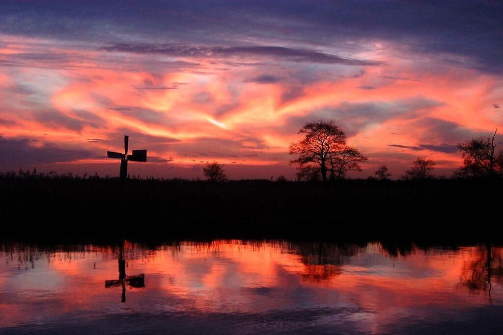 Un atardecer sobre una masa de agua con una cruz al frente.