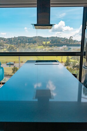 Una cocina moderna con un amplio ventanal que da a un paisaje verde y una carretera.