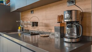 Une cuisine moderne équipée d’une machine à café, d’un bloc à couteaux et d’un panier métallique posé sur le plan de travail.