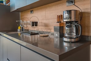 Eine moderne Küche mit Kaffeemaschine, Messerblock und Drahtkorb auf der Arbeitsfläche.