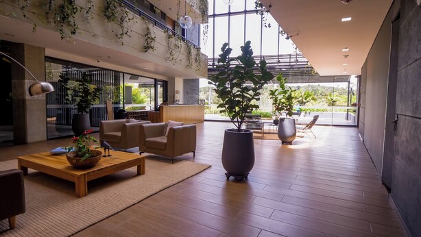 Un hall d’entrée spacieux, doté d’un haut plafond, de grandes fenêtres et de plantes d’intérieur.