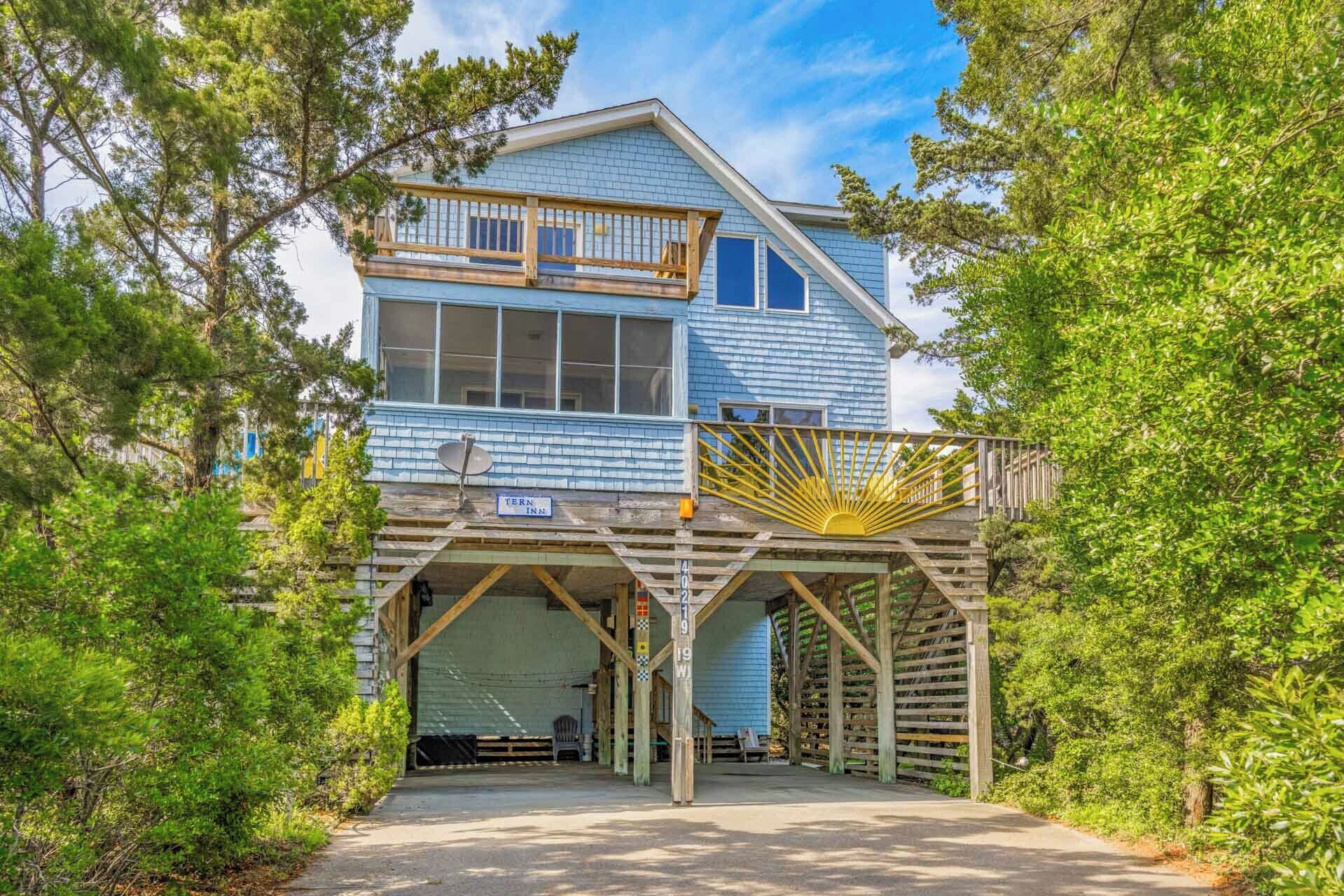 A two-story building with a covered parking area and a wooden deck.