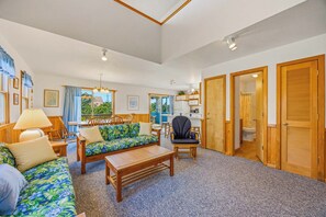 A spacious living room with a sofa, a dining table, and a kitchen area. - Charming Oceanside Home in Avon with Sun Deck (Avon)
