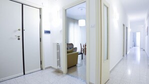 A hallway with a closed door, a radiator, a sofa, and a dining area with chairs and a table. - Spacious apartment with a balcony, perfect for up to six people thanks to three double bedrooms. The accommodation is located in the Torrione neighborhood, a strategic area just a short distance from the city center and the seafront, well-served by all m (Salerno)