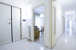 Ein Flur mit geschlossener Tür, einem Heizkörper, einer Couch und einem Essbereich mit Stühlen und einem Tisch.