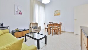 A modern living room with a sofa, coffee table, dining table, chairs, a lamp, and artwork on the walls. - Spacious apartment with a balcony, perfect for up to six people thanks to three double bedrooms. The accommodation is located in the Torrione neighborhood, a strategic area just a short distance from the city center and the seafront, well-served by all m (Salerno)