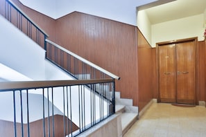 Eine Treppe mit Holzvertäfelung und Metallgeländer, die zu einem Raum mit einer Holztür führt.