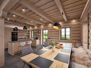 A modern kitchen with wooden beams, a dining area with a large table, and a view of the outdoors. - Chalupa Dva by Interhome (Roprachtice)