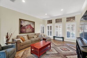 A spacious living room with a large sofa, a coffee table, and a painting on the wall. - Roaring Fireplace Family Basecamp Midland Tx 4 Bedroom Home (Midland)