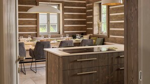 A modern kitchen with wooden cabinetry and a central island, dining area with chairs and a table, and large pendant lights. - Chalupa Raz by Interhome (Roprachtice)