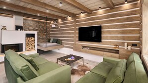 A modern living room with a stone fireplace, green sofas, a flat-screen TV mounted on a wooden wall, and a ceiling with exposed beams. - Chalupa Raz by Interhome (Roprachtice)