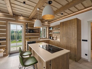 Eine moderne Küche mit Holzschränken, einer zentralen Kochinsel und Pendelleuchten.