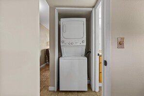 A compact laundry room with a washer and dryer, a doorbell, and a tiled floor. - Kihei Beach, #108 1 Bedroom Condo (Kihei)