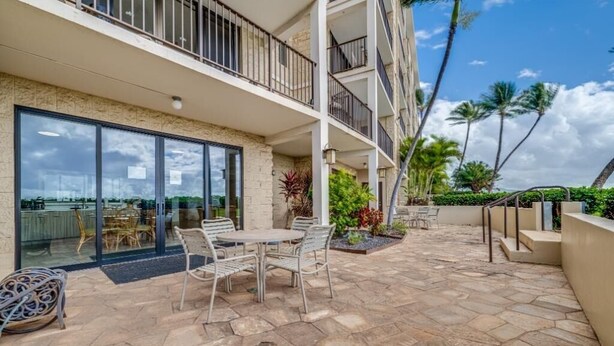 Un edificio de varios pisos con balcones, mobiliario exterior y vistas a palmeras.