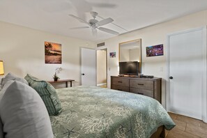 A bedroom with a bed, a dresser, a television, and a ceiling fan. - Kihei Beach, #108 1 Bedroom Condo (Kihei)