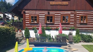 Un edificio de madera con piscina, un letrero que dice 'Il tri medvedu' y asientos exteriores.