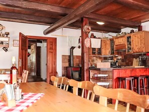 Eine rustikale Küche mit Holzausbau, einer Ziegelwand und einem Essbereich mit einem Holztisch und Stühlen.