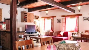 Una sala de estar acogedora con una mesa de madera, sillas, un sofá y un televisor.