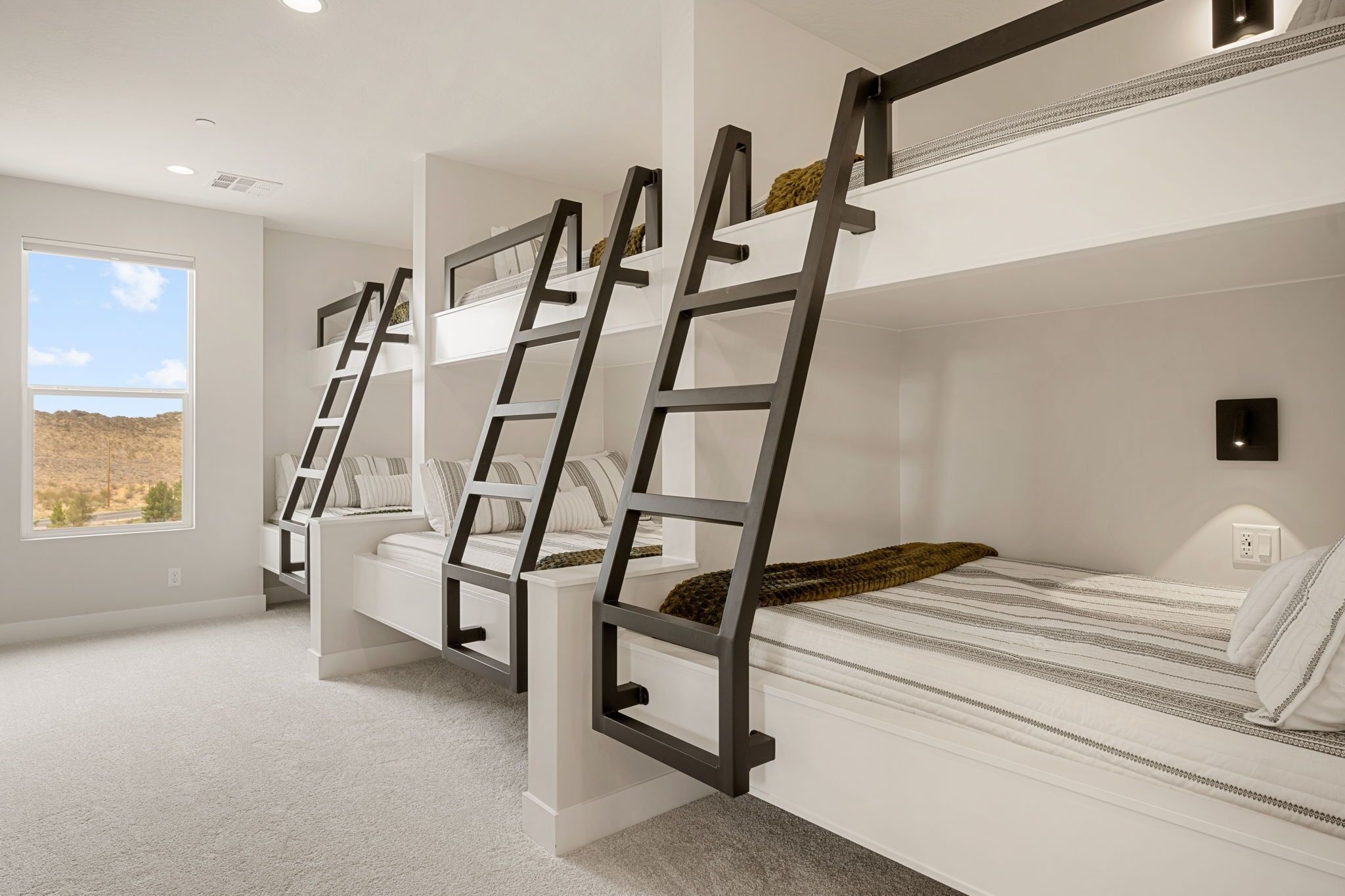 A bunk bed room with a ladder, a window with a view, and a white wall.