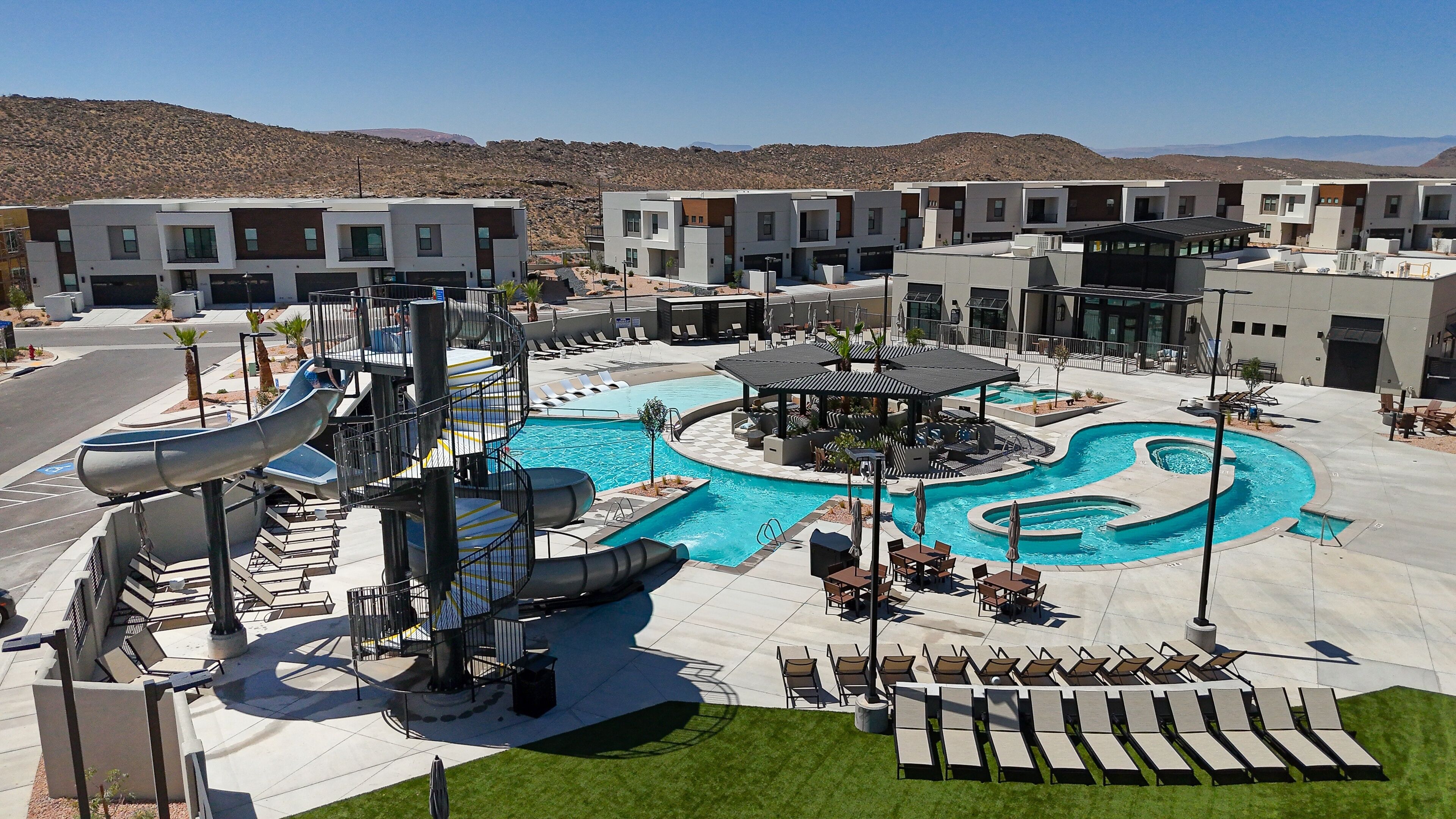 A modern hotel with a swimming pool, lounge areas, and a water slide.