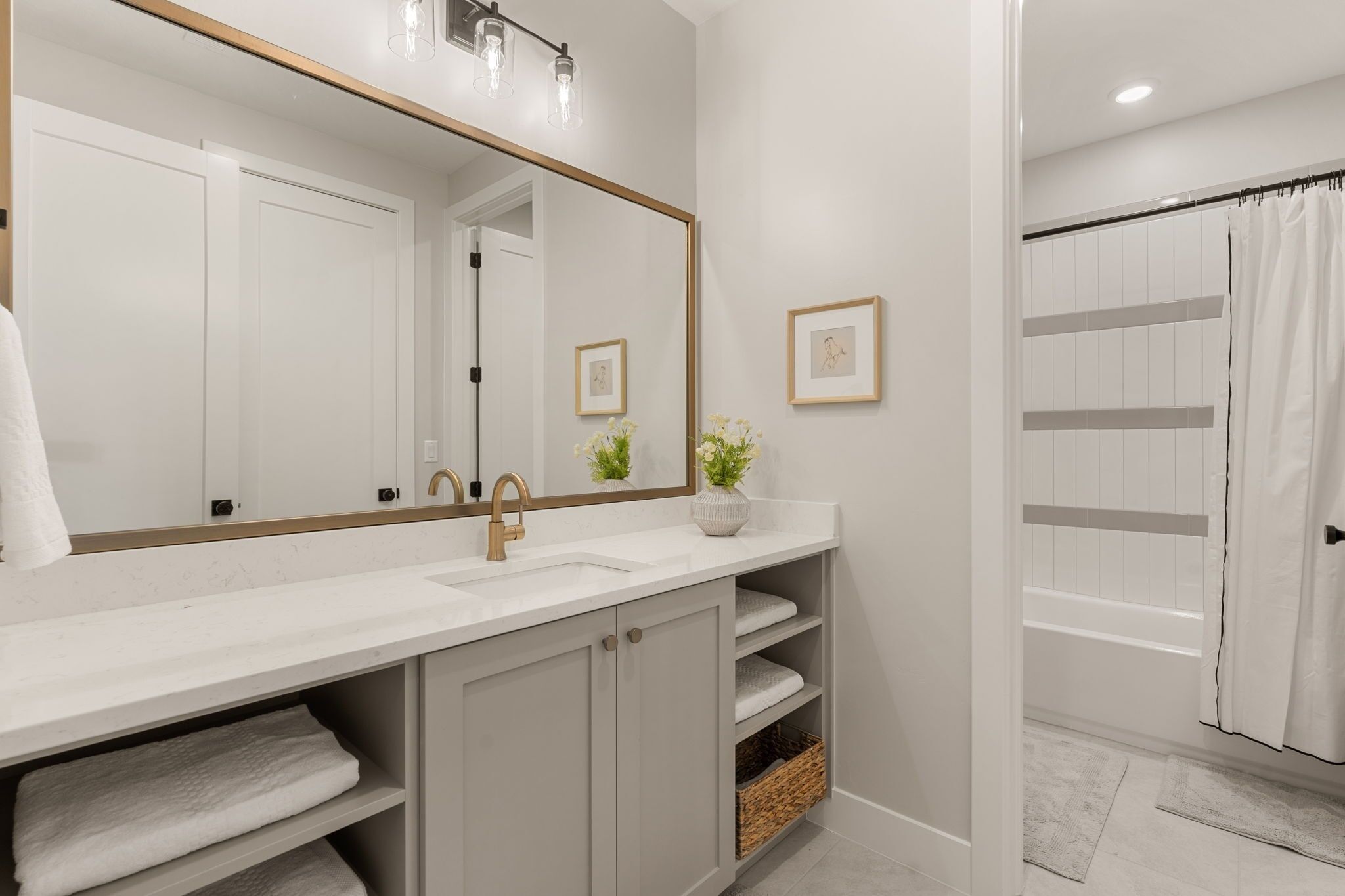 A bathroom with a large mirror, two sinks, a shower curtain, and a towel rack.