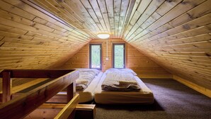 Ein kleines Schlafzimmer im Dachgeschoss mit zwei Betten, einer Holztreppe und einem Oberlicht.