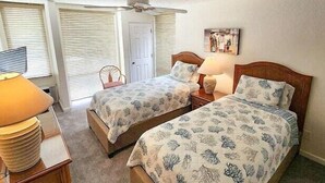 A bedroom with two beds, a ceiling fan, a door, and a lamp. - Hale Kamaole 271- Paradise Found (Kihei)