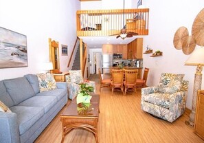 Ein geräumiger Wohnbereich mit Sofa, Sesseln, Couchtisch, Esstisch und einer Küche im Hintergrund.