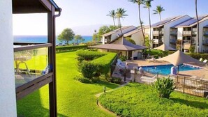 A hotel with a pool, palm trees, and a view of the ocean. - Hale Kamaole 271- Paradise Found (Kihei)